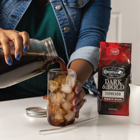 Woman pouring Community Coffee cold brew into glass
