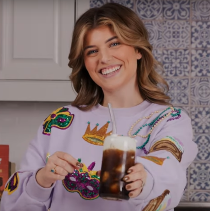Woman holding glass of iced coffee with cold foam on top